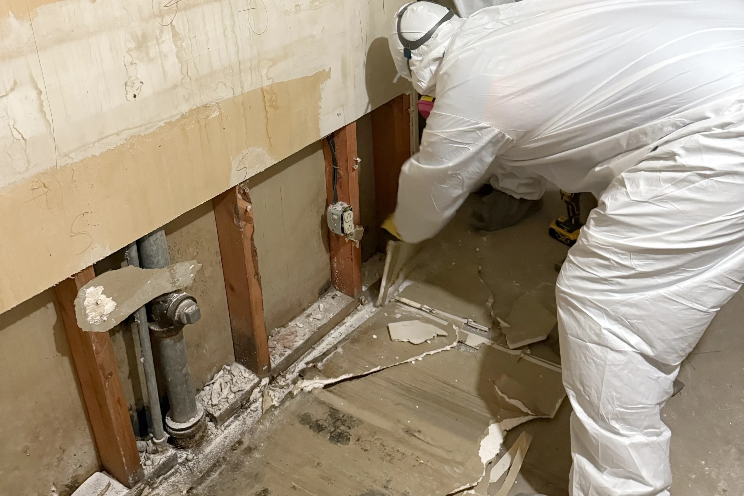 Flood damaged sections of drywall are removed by a demo expert in a hazmat suit at a home in St. George, UT.